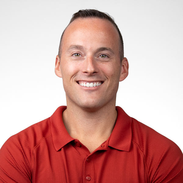 A smiling man with short brown hair wears a red collared shirt, representing medbridge.